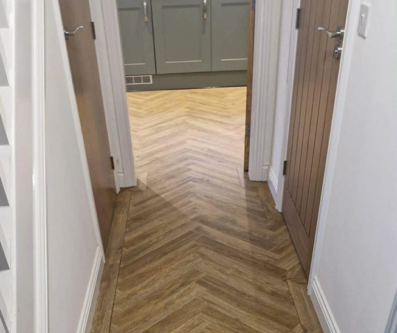 A wood effect floor running the length of a hallway between painted doors
