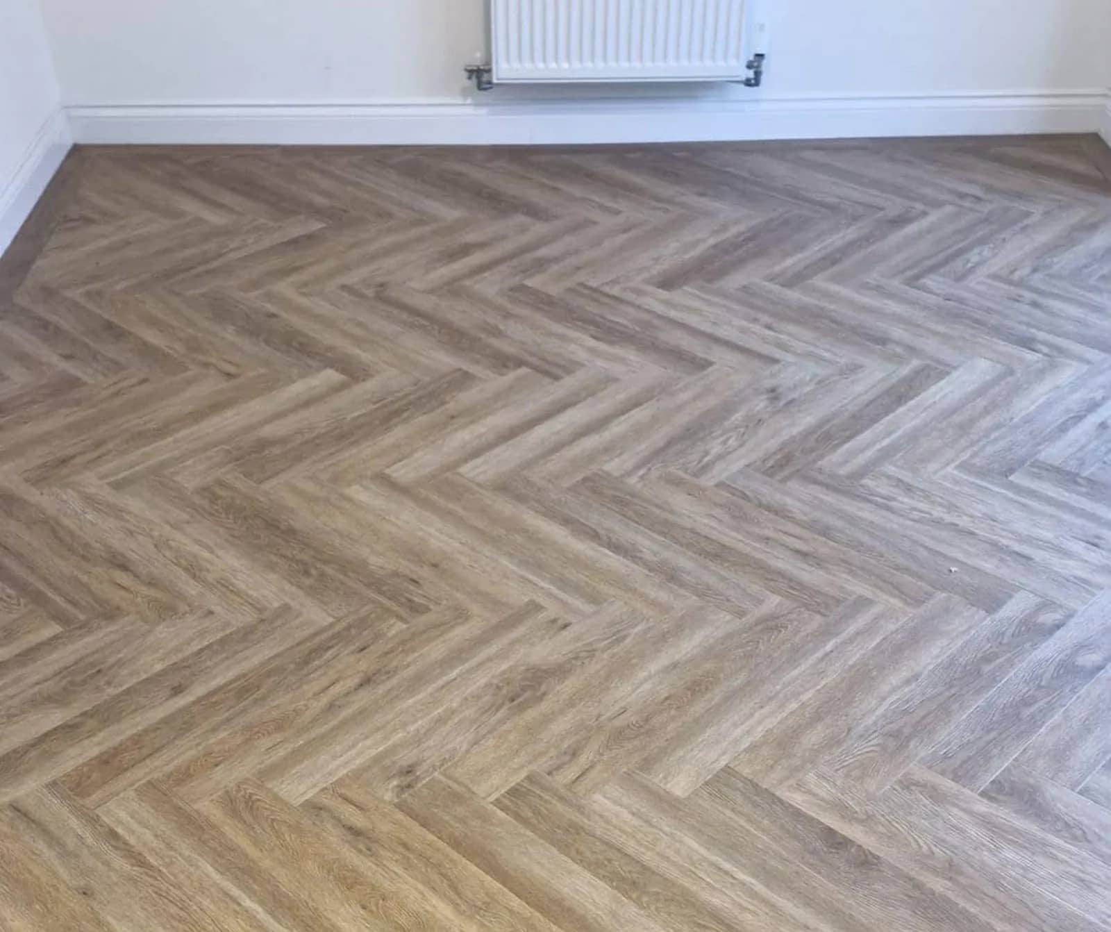 Herringbone wood effect flooring in an empty room