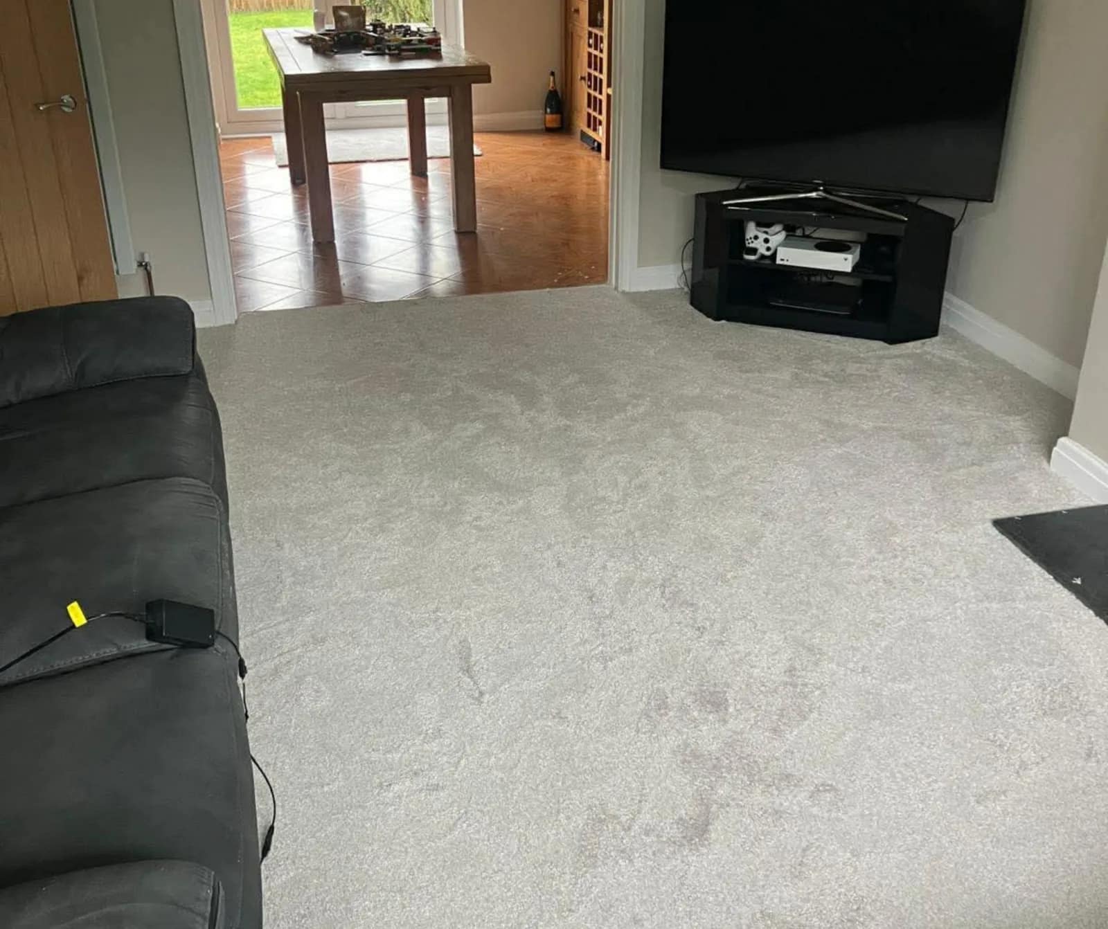 A light coloured carpet fitted through a living room and on into the room beyond