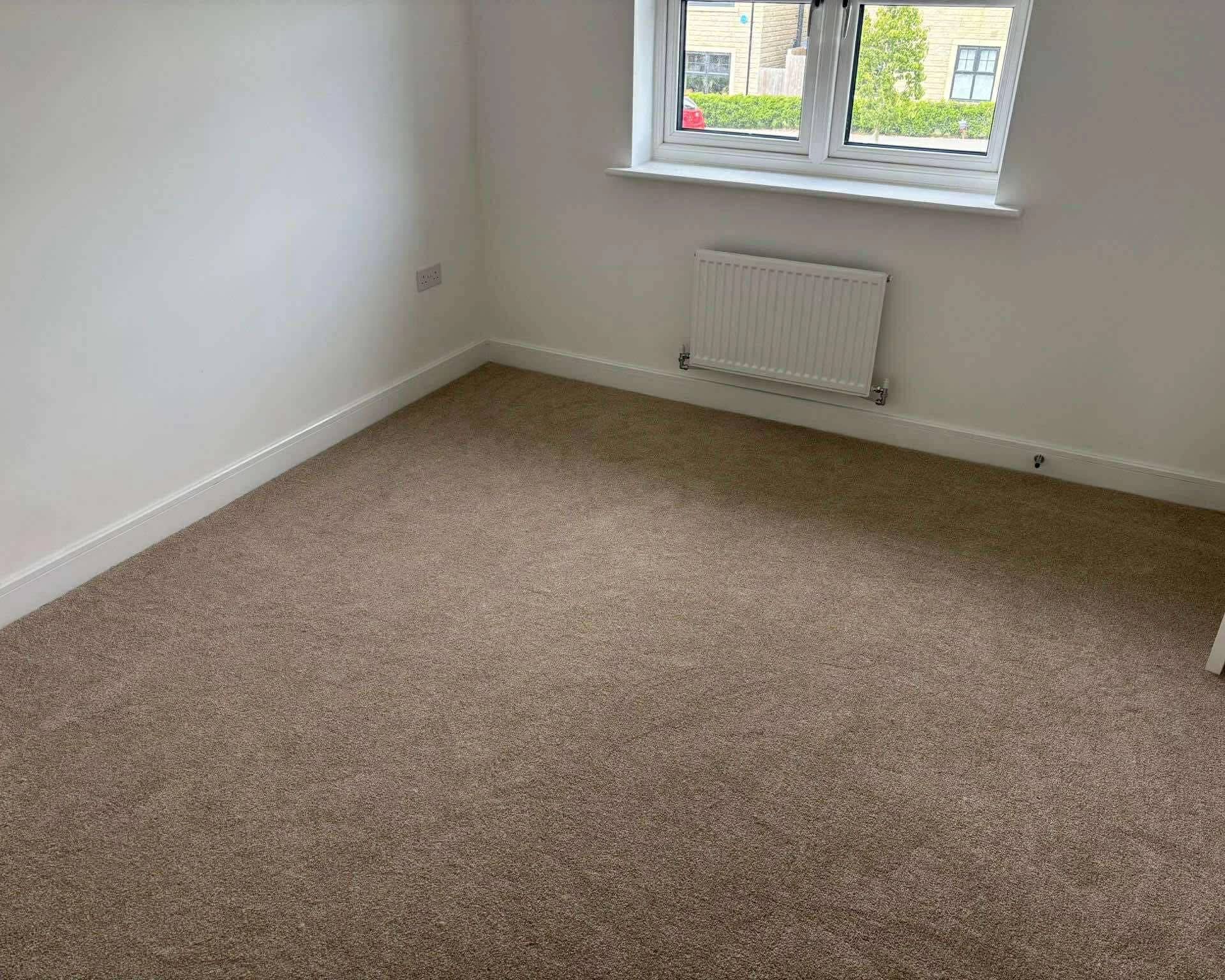 Beige carpet fitted wall to wall in a bedroom, cut in under the window