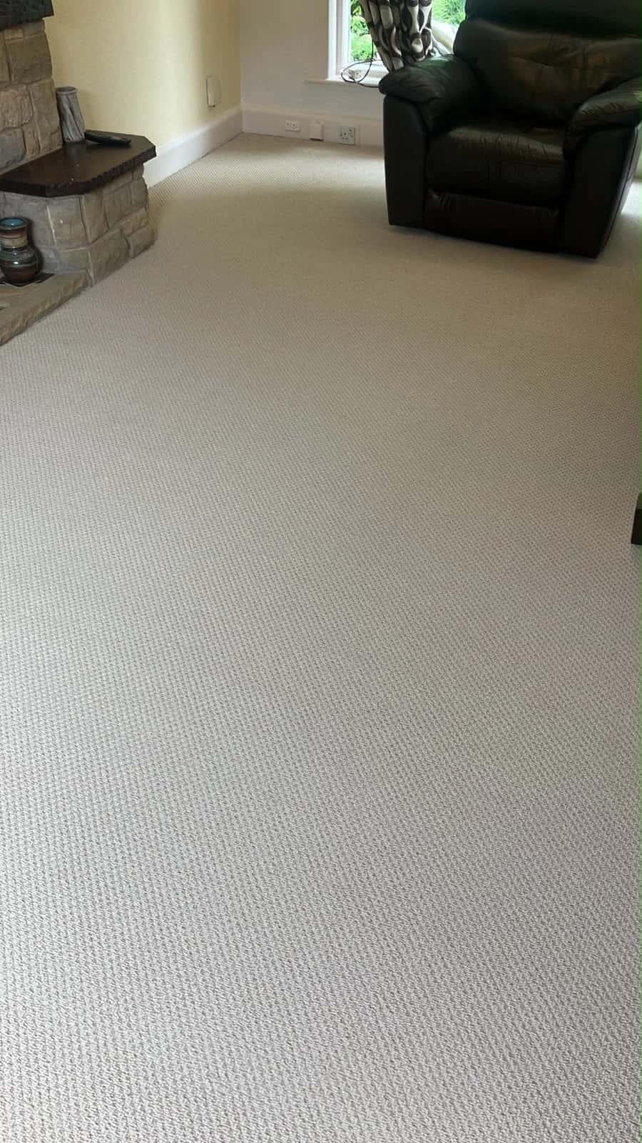 Cream carpet fitted around a stone fireplace