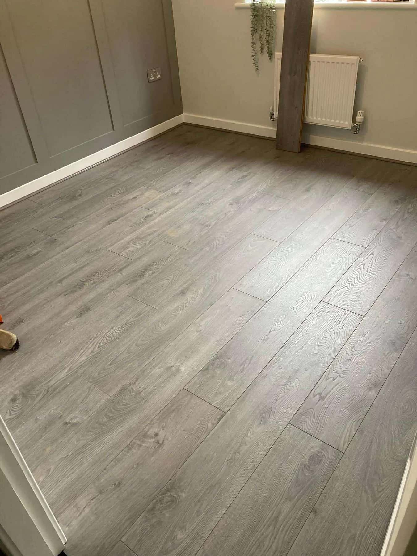 Grey plank flooring fitted up to the skirting in a room