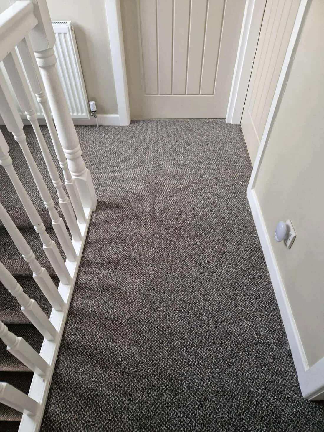 Grey carpet across a landing and down past the banister