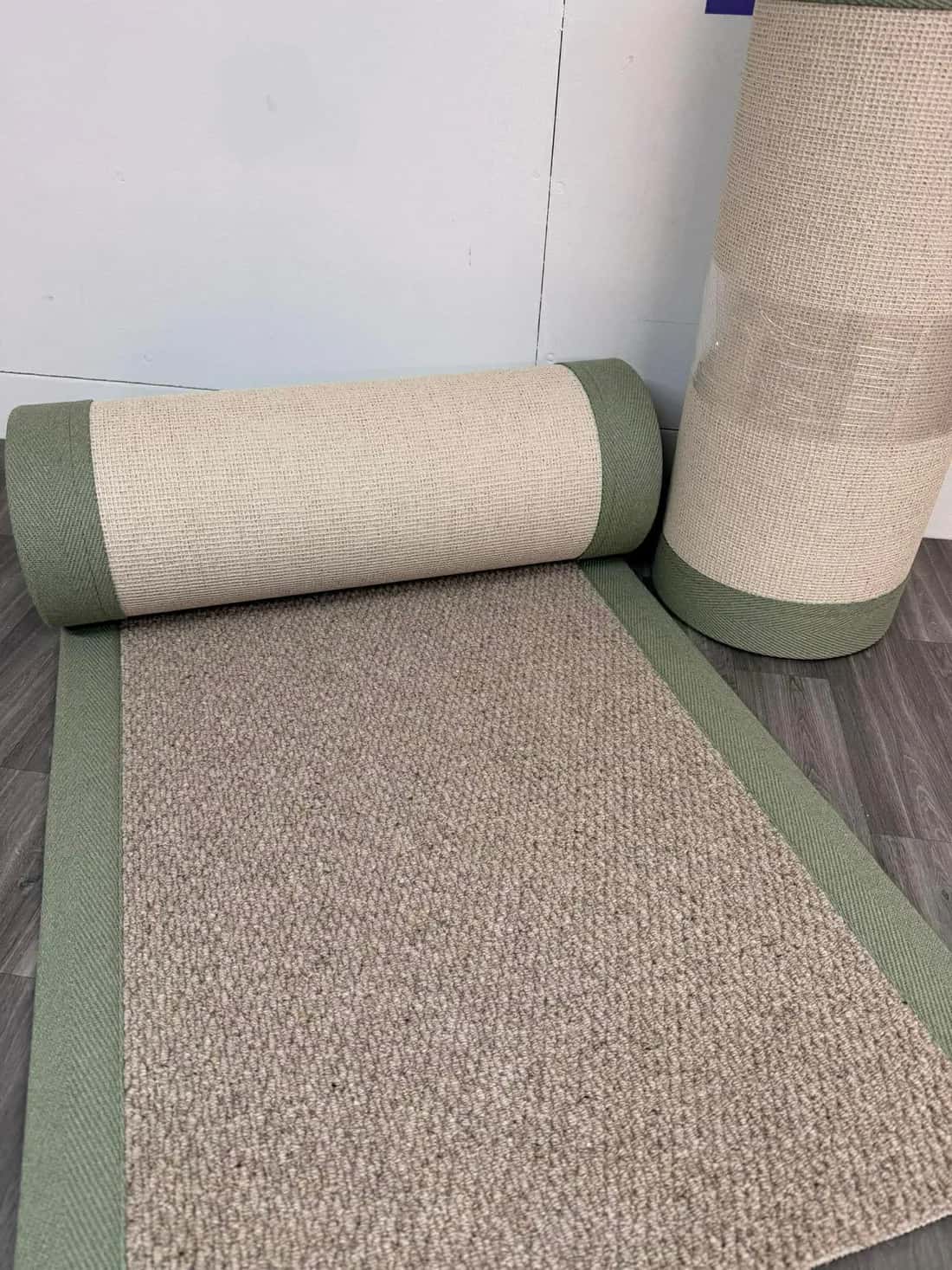 A rug bound with a green border, rolled and finished