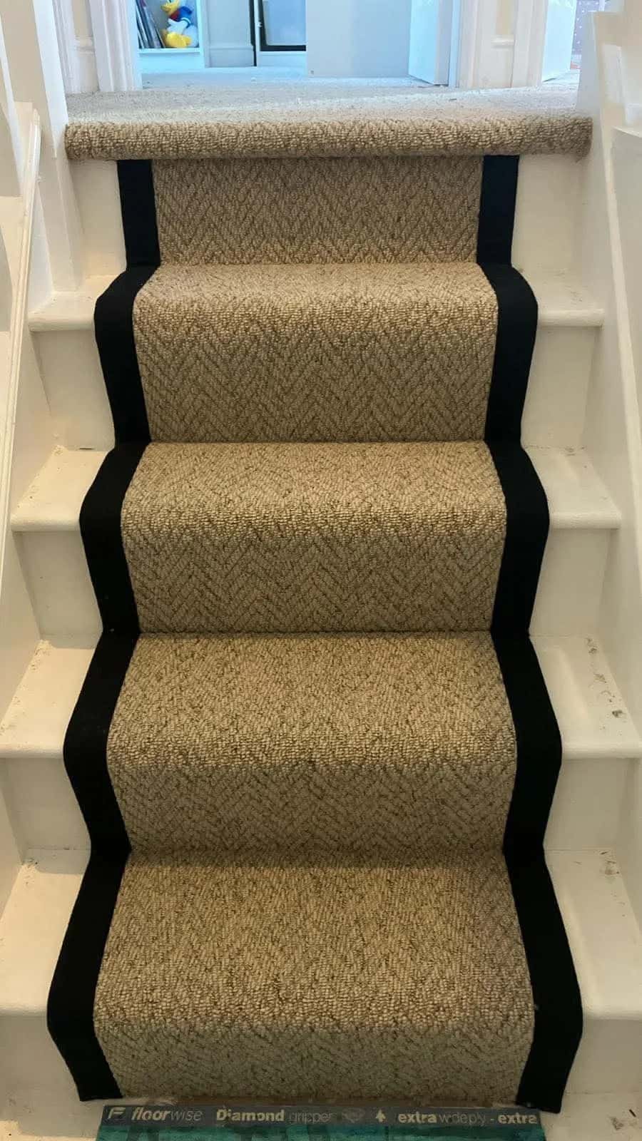 A herringbone runner with a black border on painted stairs