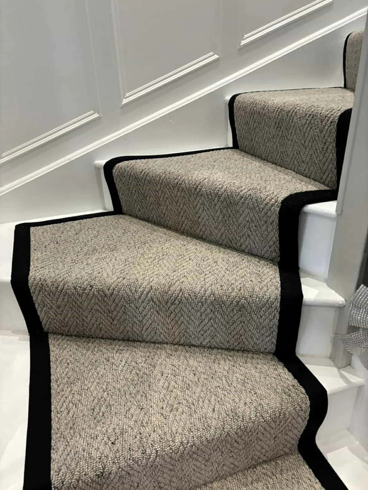 A pale runner with a black border turning a winder staircase