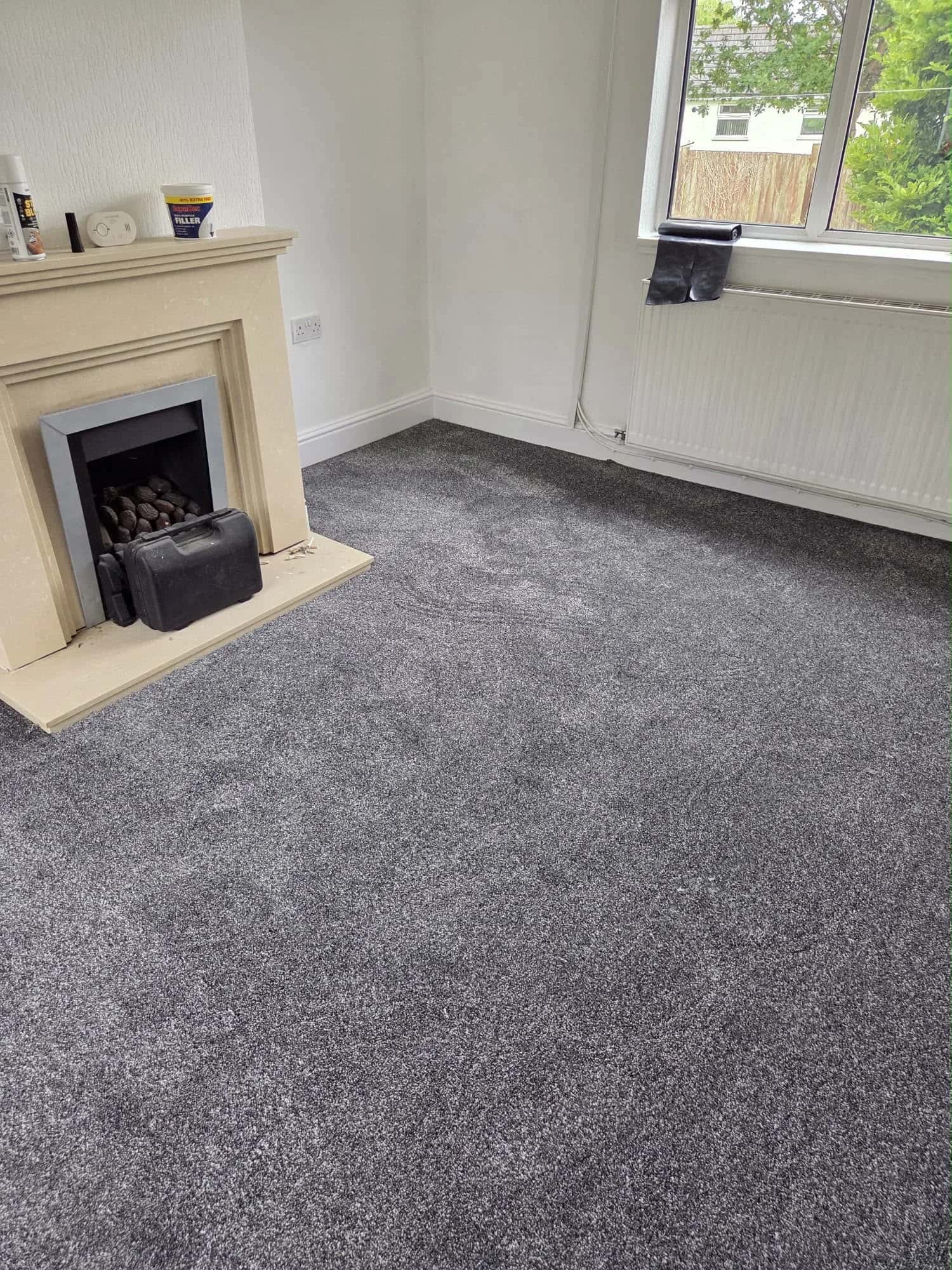 Grey carpet fitted in a living room with a fireplace