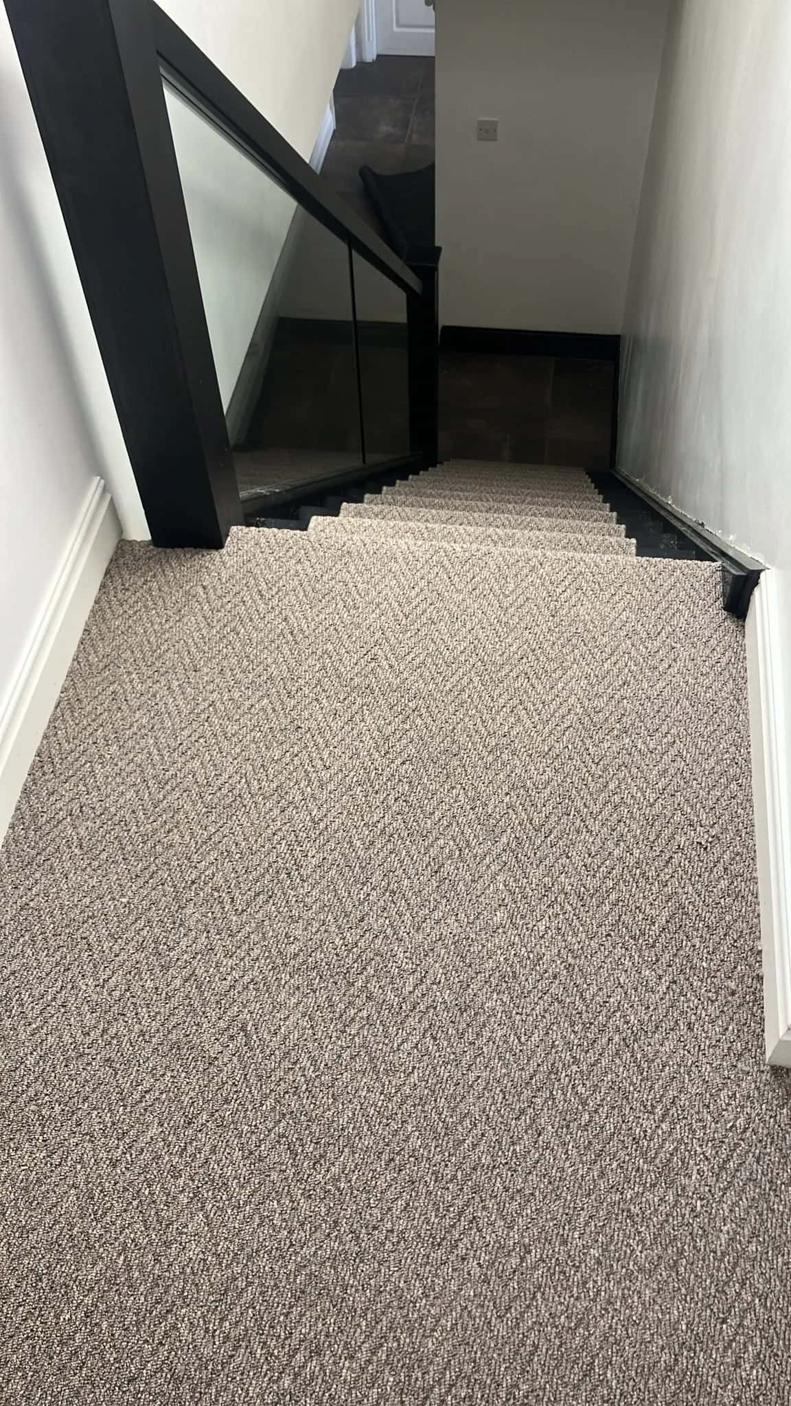 Herringbone carpet in a hall with a glass balustrade