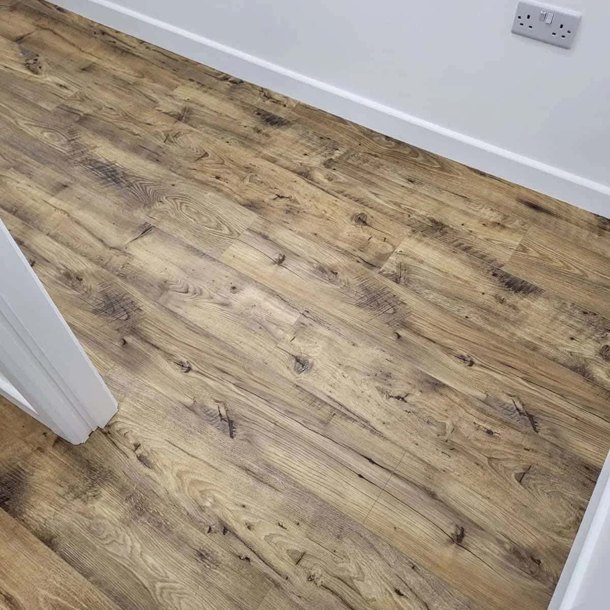 Oak effect plank flooring running up to a white painted skirting