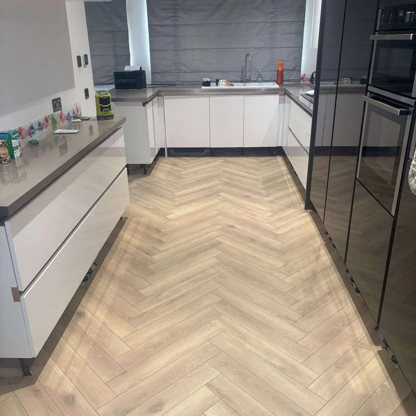 Herringbone luxury vinyl tile laid through a modern fitted kitchen