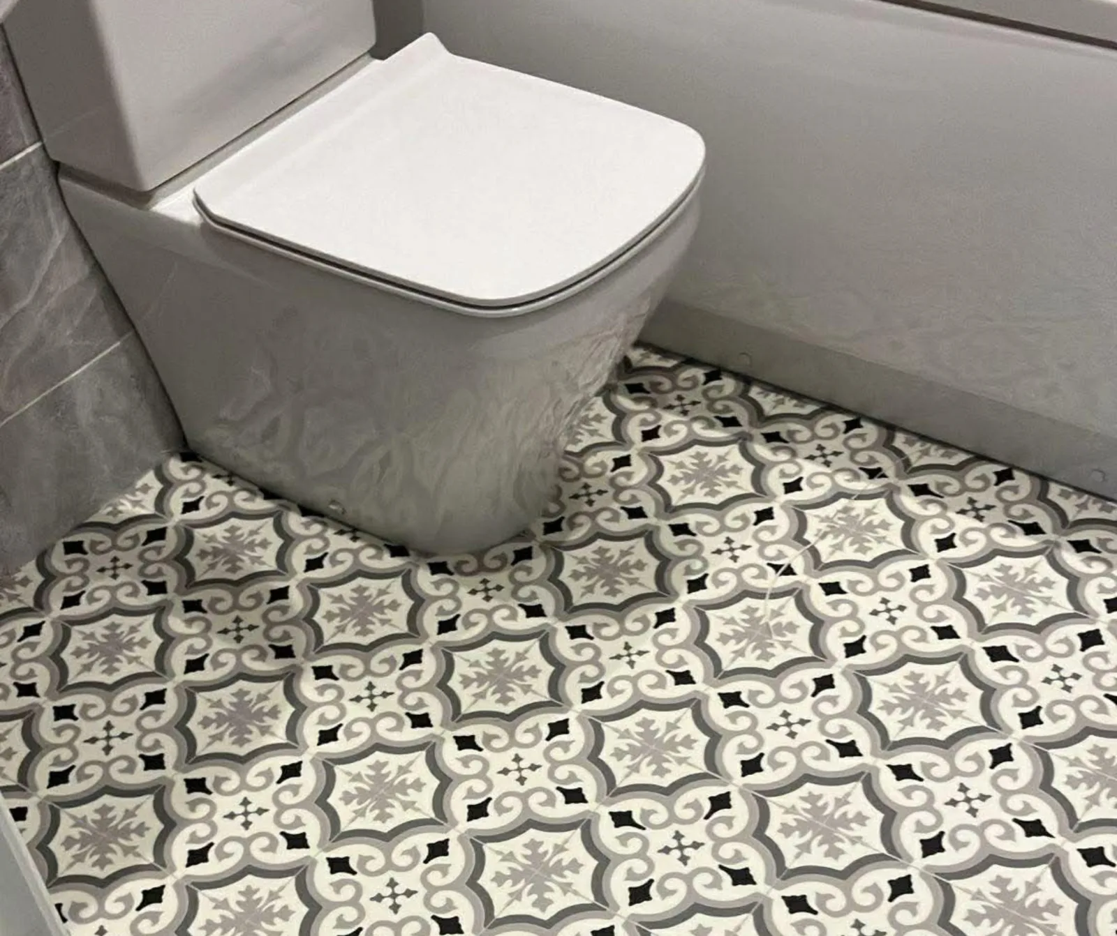 Patterned vinyl flooring fitted in a bathroom, cut neatly around the toilet and bath panel