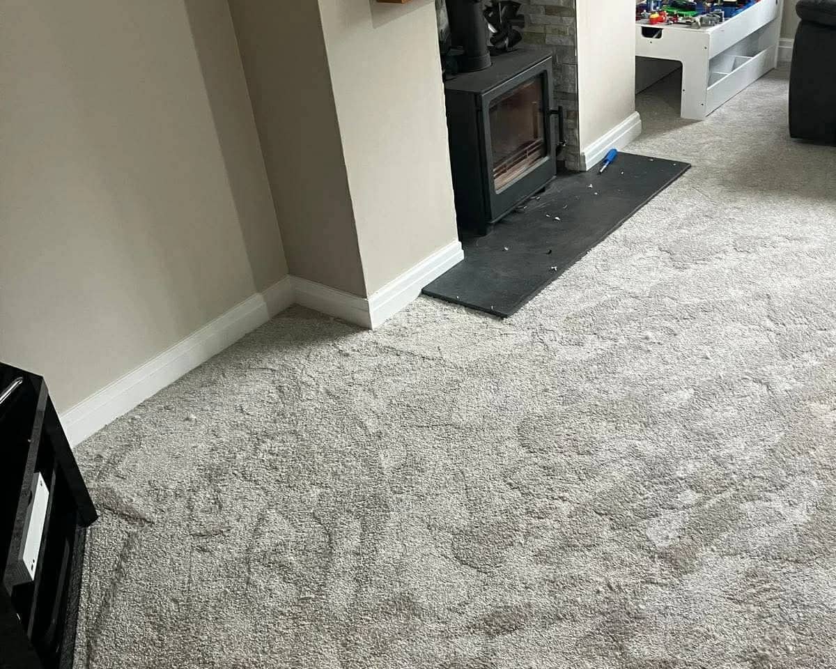 Grey carpet fitted through a living room up to a slate hearth and log burner