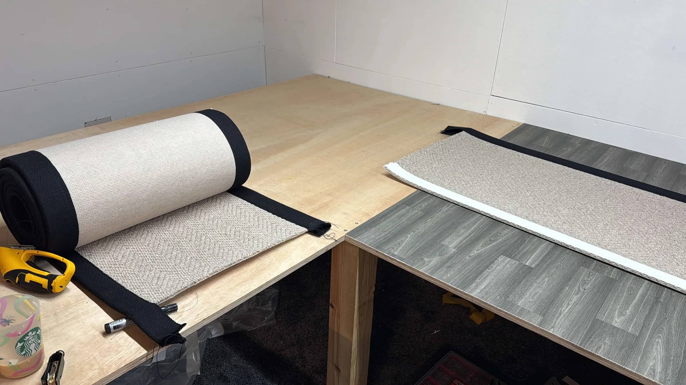 A carpet runner part-bound on the workshop bench with a tape measure, binding tape and a straight cut edge alongside it