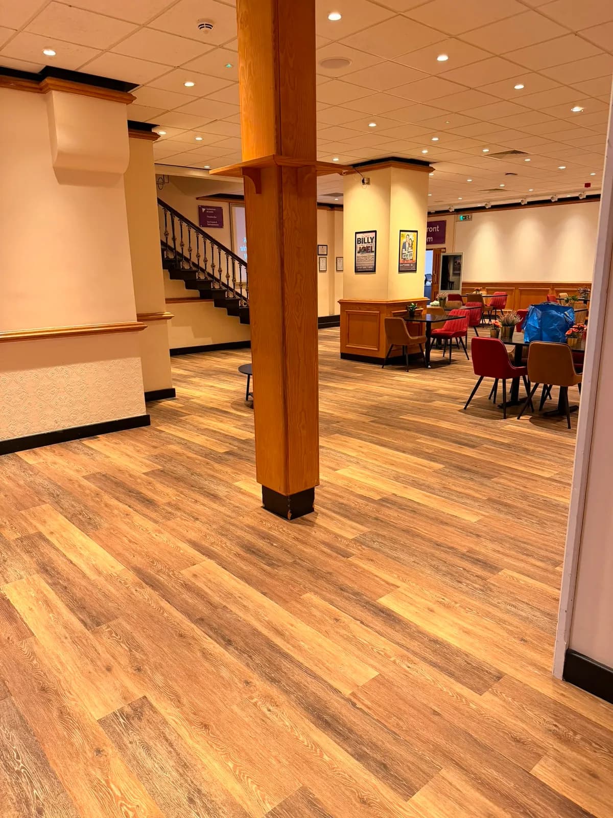 The finished foyer in wood effect vinyl plank, running past the timber column to the foot of the staircase