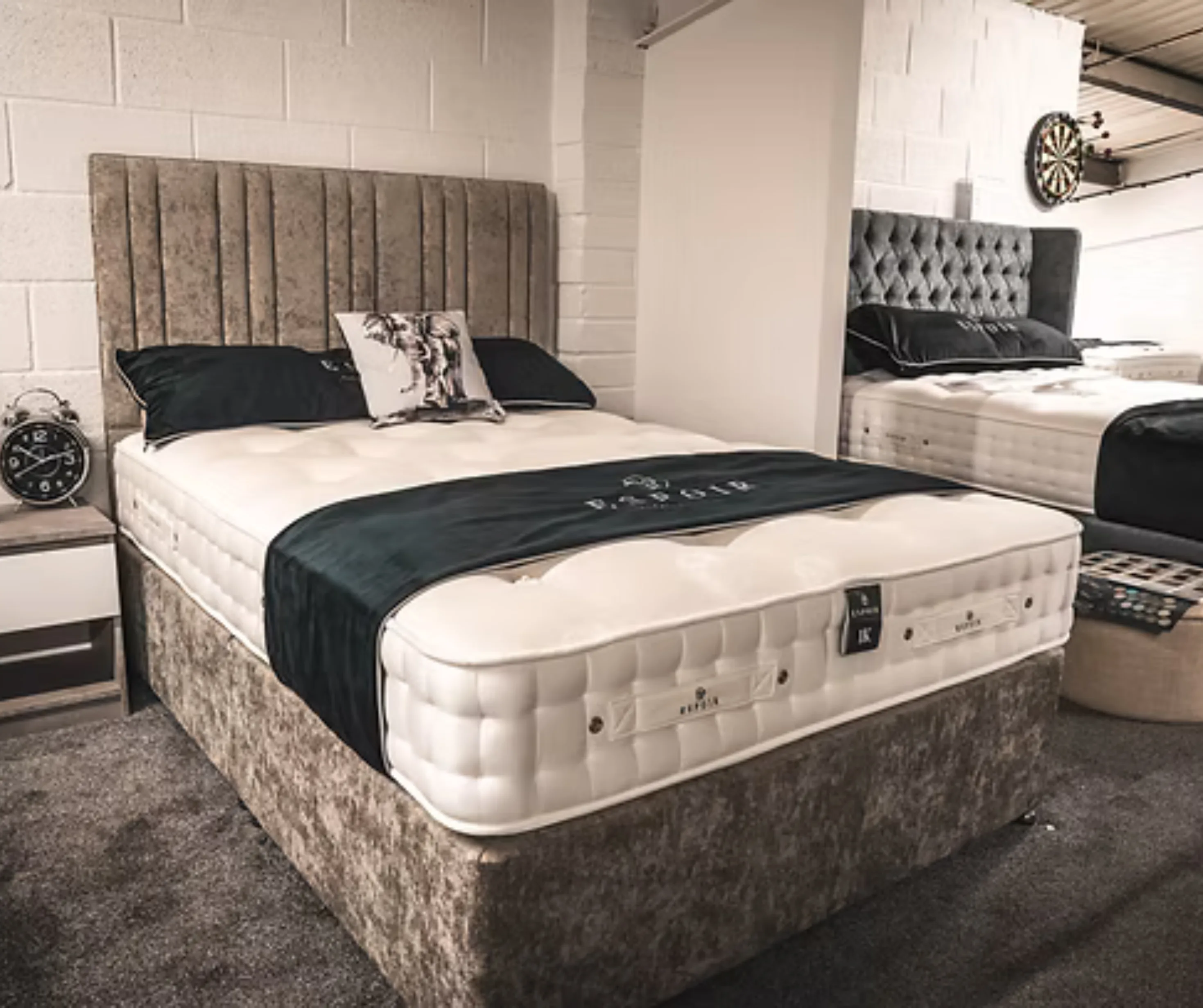 A deep quilted mattress on a divan base with a buttoned headboard, made up on the showroom floor